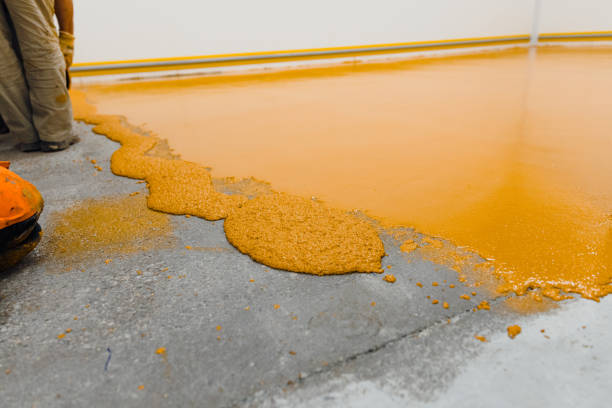 Bright orange textured garage floor coating being spread onto concrete for a durable finish.