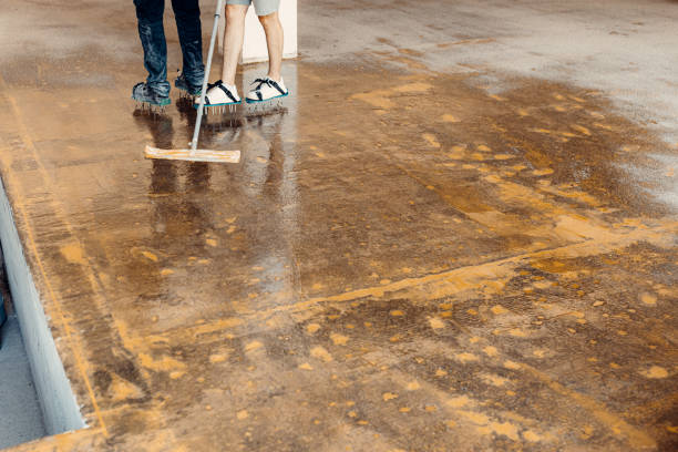Applying chemicals for garage floor coating prep.