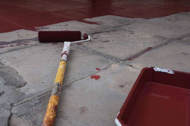 Garage floor coating does not fix all problems. 2 Applying red garage floor coating to a concrete surface with a roller.