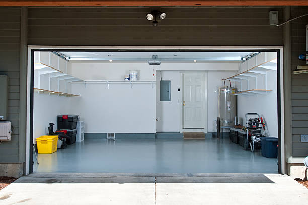 Clean, empty garage featuring a new light grey garage floor coating and organized shelving.