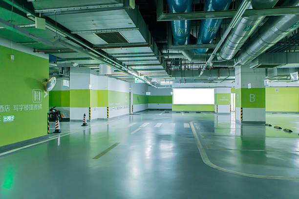 Spacious underground parking garage with reflective grey garage floor coating and bright green walls.