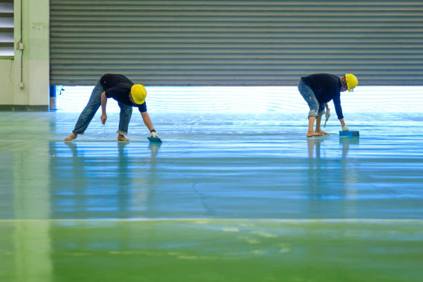 Workers apply a new Garage Floor Coating, creating a smooth, reflective surface.