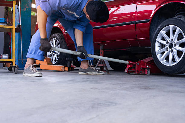 Mechanic lifting red car with jack on a clean garage floor coating.