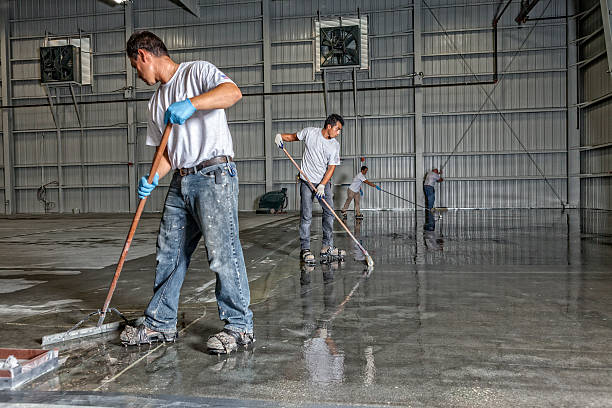 Team of professionals applying a durable Garage Floor Coating in a large warehouse.