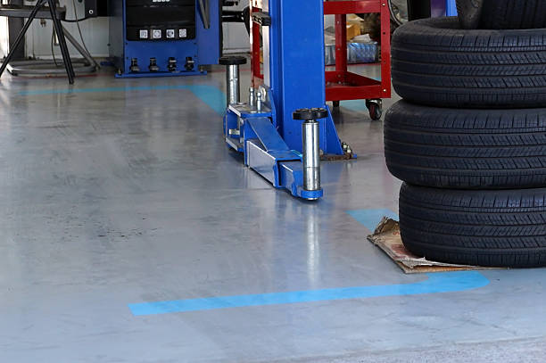 Clean garage floor coating with blue lift, markings, and stacked tires.