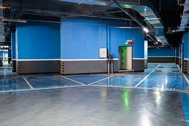 Empty underground parking garage featuring a dark blue garage floor coating and vibrant walls.