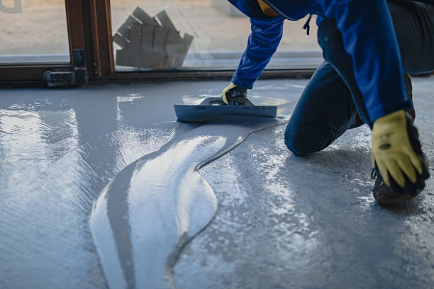 Professional applying a fresh, protective grey garage floor coating with specialized tools.