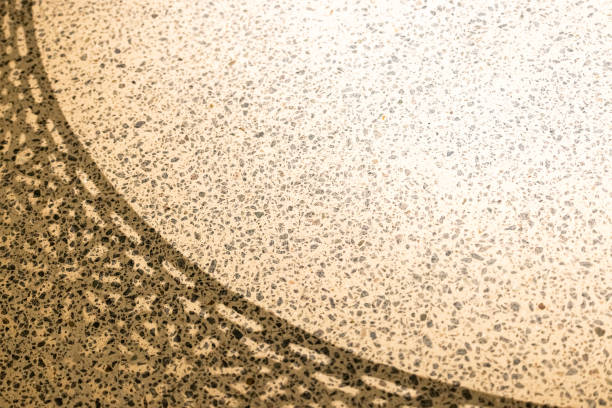 Close-up of a durable, speckled garage floor coating with a decorative curved shadow.