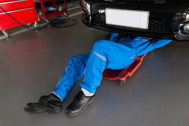 Mechanic on creeper working under car on a smooth garage floor coating.